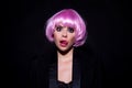 Funny woung woman tongue lick lips. Close-up portrait of amazing female model in pink wig. Studio photo funny surprised