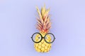 Funny yellow pineapple face with glasses on violet background