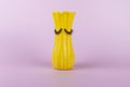 Funny yellow vase with eyes on a pink background