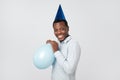 Funny young african guy inflating the balloon wearing blue party hat. Royalty Free Stock Photo