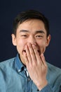 Funny young Asian man covering his mouth with palm Royalty Free Stock Photo