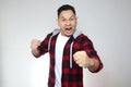 Funny young Asian man showing cynical unhappy angry facial expression putting up his fist challenge to fight Royalty Free Stock Photo