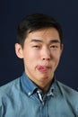 Funny young Asian man showing his tongue and looking at camera Royalty Free Stock Photo