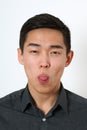 Funny young Asian man showing his tongue and looking at camera Royalty Free Stock Photo