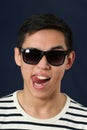 Funny young Asian man in sunglasses showing his tongue Royalty Free Stock Photo