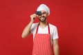 Funny young bearded male chef cook or baker man in striped apron white t-shirt toque chefs hat isolated on red Royalty Free Stock Photo