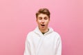Funny young blond man in white sweatshirt isolated on pink background looking into camera with shocked funny face. Suspicious guy Royalty Free Stock Photo