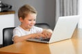 Funny young boy using a laptop computer sitting on top of a table at home Royalty Free Stock Photo