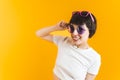 Funny young caucasian girl with two pairs of sunglasses. Gen Z humor. Isolated over orange background. Medium closeup Royalty Free Stock Photo