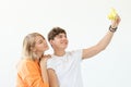 Funny young couple in love cute man and charming woman making selfie on vintage yellow film camera posing on a white