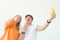 Funny young couple in love cute man and charming woman making selfie on vintage yellow film camera posing on a white