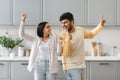 Funny young eastern couple singing together at kitchen Royalty Free Stock Photo