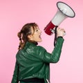 Funny young female shouting through megaphone. Young woman using loudspeaker on colored backgrounds