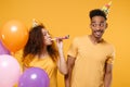 Funny young friends couple african american guy girl in birthday hat isolated on yellow wall background. Holiday party Royalty Free Stock Photo