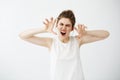 Funny young girl frightening camera with opened mouth over white background.