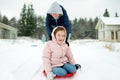 Funny young girl and her grandma having fun with a sleigh in beautiful winter park. Cute child playing in a snow Royalty Free Stock Photo
