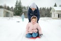 Funny young girl and her grandma having fun with a sleigh in beautiful winter park. Cute child playing in a snow Royalty Free Stock Photo