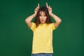 Funny young girl make horns by fingers, making faces, showing tongue, having fun, grimacing, fooling, teasing Royalty Free Stock Photo