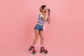 Funny young lady with camera taking photos. Full length view of pinup girl in roller skates Royalty Free Stock Photo