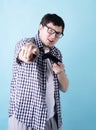 Funny young man playing video games holding a joystick isolated on blue background