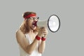 Funny young man in retro sportswear yelling in megaphone isolated on gray background