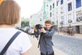 Funny young photographer photographing a girl model on camera in the streets of the town