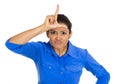 Funny young woman displaying loser sign on his forehead