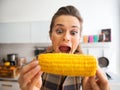 Funny young woman eating boiled corn