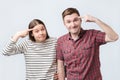 Funny young woman and man have dissatisfied facial expressions, keep index fingers on temples, Royalty Free Stock Photo