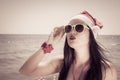 Funny young woman in Santa Claus hat and sunglasses on a beach Royalty Free Stock Photo