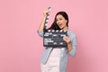Funny young woman in striped jacket holding classic black film making clapperboard isolated on pink pastel wall Royalty Free Stock Photo