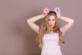 Funny young woman with tasty donuts on color background