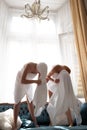 Funny young woman in pajama morning leisure time in bedroom at home. Excited girlfriends in white bathrobes and towels
