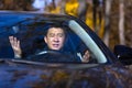 Furious angry asian man standing in a traffic jam beeps and hurries. Sitting in the car. Irritated young business male tired Royalty Free Stock Photo