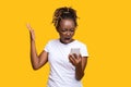 Furious black lady standing on yellow and screaming at smartphone