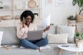 Furious black woman talking on cellphone while working with papers and laptop