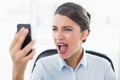 Furious classy brown haired businesswoman yelling at her mobile phone Royalty Free Stock Photo