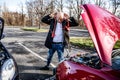 Furious driver trying to start broken car with jumper cables.