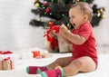 Furious emotional baby yelling, sitting with decorations near Christmas tree Royalty Free Stock Photo