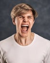 Furious, enraged young man over gray background