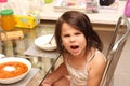 furious little girl with long hair screams at the dinner table