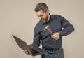 Furious man break laptop hitting notebook with hammer grey background, computer rage