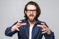 Furious young man wearing glasses isolated on grey studio background shout annoyed by loud noise Royalty Free Stock Photo