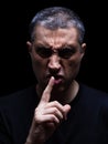 Furious mature man with an aggressive look making the silence sign in a violent and threatening way