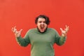 Furious overweight man with a curly hair, standing on a red background, feeling angry and frustrated, screaming, gesticulating and Royalty Free Stock Photo