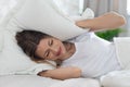 Furious sleepless young woman covering her head with pillow