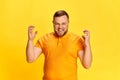 Portrait of angry bearded man screaming and spreading hands to sides over yellow background