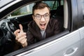 Furious young man is looking at the camera while sitting at his car. He is screaming at someone. Angry driver concept Royalty Free Stock Photo