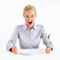 Feed me now. Furious young woman sitting in front of an empty plate while holding her knife and fork. Royalty Free Stock Photo