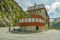 Two cyclists driving next to abandoned hotel Belvedere through Furkapass mountain pass in Swiss Alps